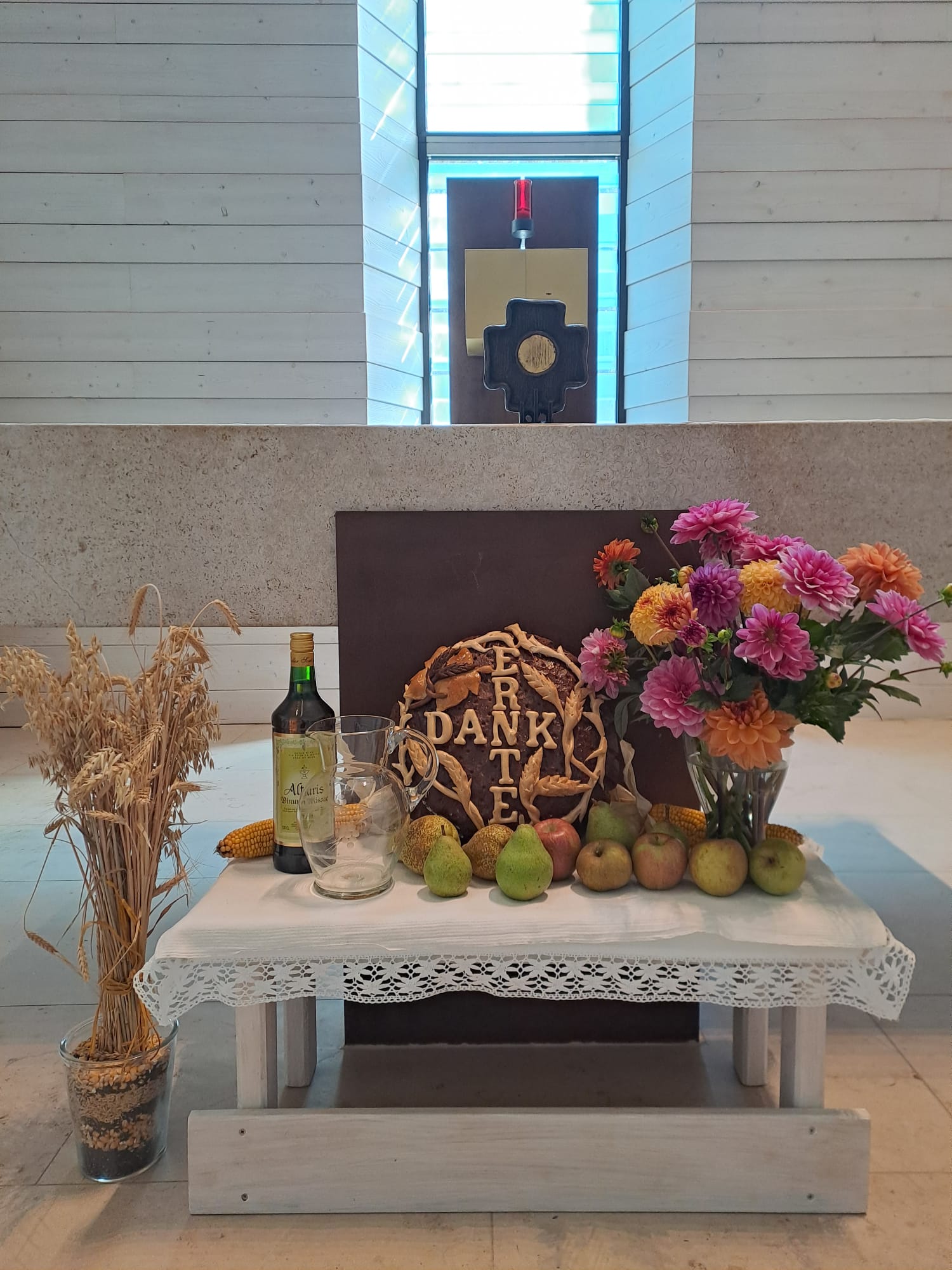 Brot, Wein, Getreide und Blumen vor einem Altar